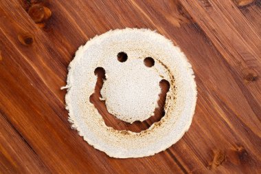 Top down view of an used, round sandpaper disk, looking like a smiling face, on a dark wood surface. Eco friendly industrial concept. clipart