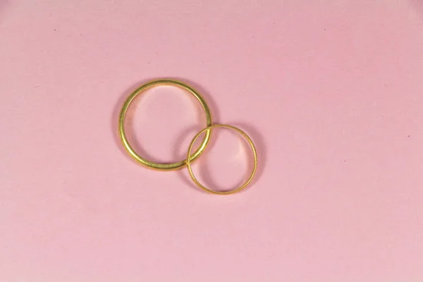 분홍색 배경에 금으로 결혼반지 — 스톡 사진