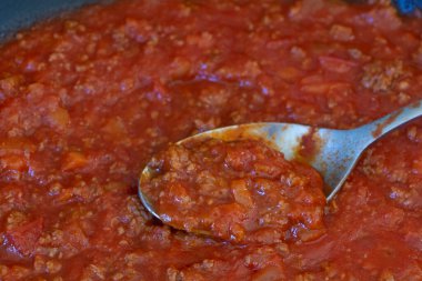 Bolonez sosu kızartma tavasında ve kaşıkta pişiyor.