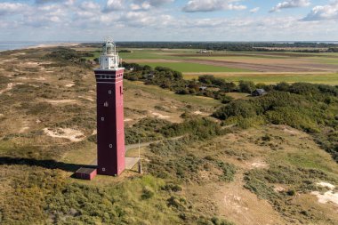 Güneşli bir günde antik deniz fenerinin küçük bir kasabanın üzerindeki manzarası.
