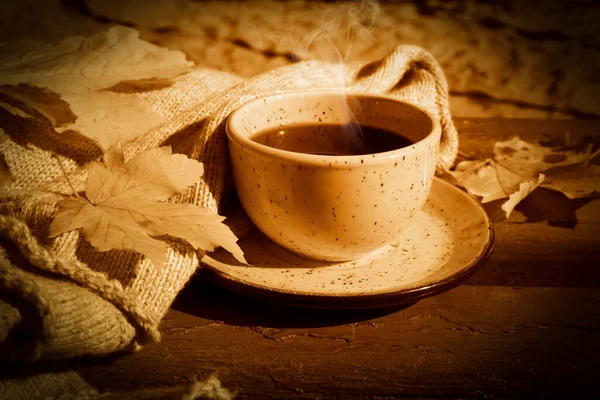 cup of coffee, autumn maple leaf, scarf on a wooden background