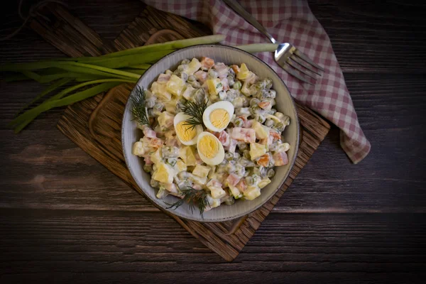 Olivier salatası, ahşap arka planda yeşil soğan.