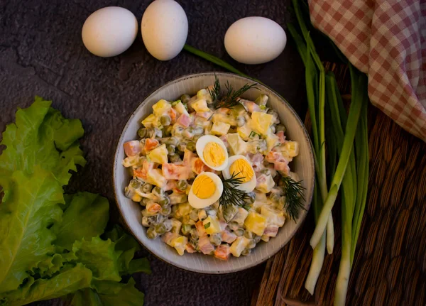 Olivier salatası, ahşap arka planda yeşil soğan.