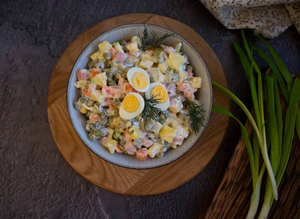 Olivier salatası, ahşap arka planda yeşil soğan.