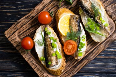 sprats in a can, fresh dill on wooden background