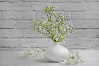 Tuğla bir arka planda vazoda çikila çiçeği