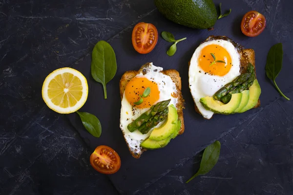 sandwich with egg, avocado, asparagus on old background
