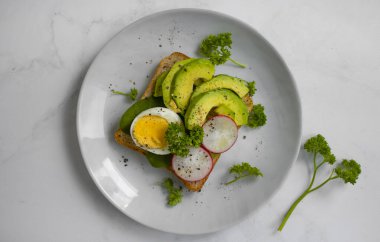 Yumurtalı sandviç, avokado, eski arkaplanda turp yeşili.