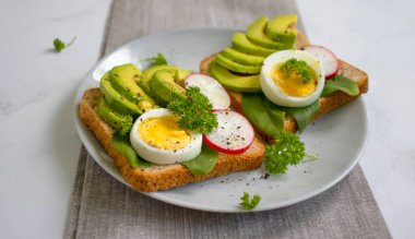 Yumurtalı sandviç, avokado, eski arkaplanda turp yeşili.