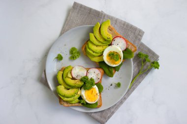 Yumurtalı sandviç, avokado, eski arkaplanda turp yeşili.