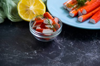 Koyu arkaplanda bir tabakta yengeç çubukları