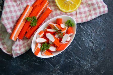 Koyu arkaplanda bir tabakta yengeç çubukları