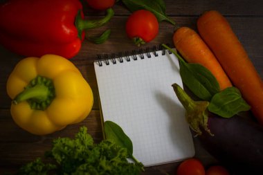 Taze sebzeler, tahta arka planda boş not defteri.