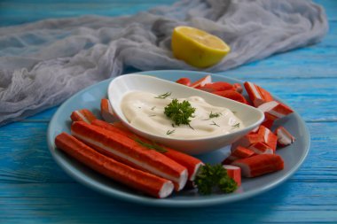 Yengeç sopaları, ahşap arka planda bir tabakta sos.