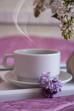 Bir fincan kahve, dairede leylak çiçeği.