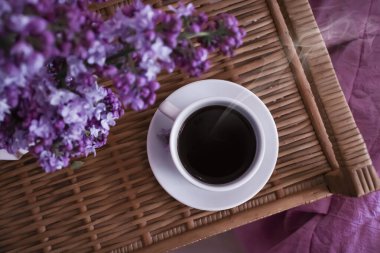 Bir fincan kahve, dairede leylak çiçeği.