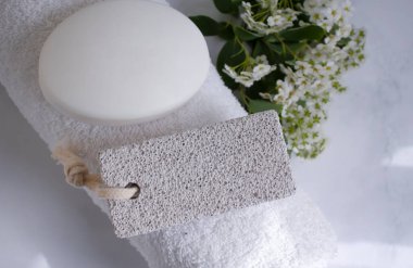 Ayaklar için sünger taşı, havlu, çiçek, arka planda sabun