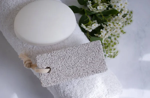 Ayaklar için sünger taşı, havlu, çiçek, arka planda sabun