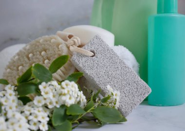 Ayaklar için sünger taşı, havlu, çiçek, arka planda sabun