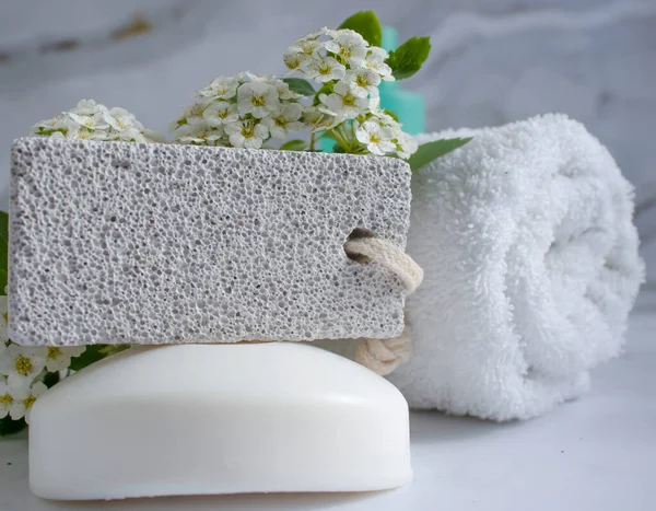 pumice for feet, towel, flower, soap on a light background