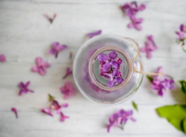 Arka planda cam bir şişede leylak özü var.