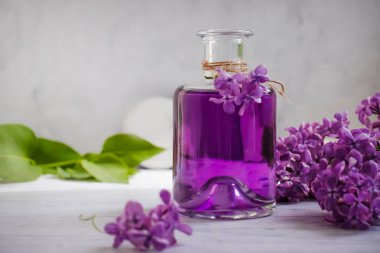 Arka planda cam bir şişede leylak özü var.