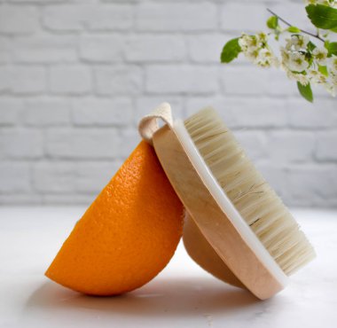 Masaj fırçası, portakal meyvesi, arka planda çiçek.