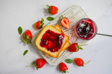 Eski bir arka planda bir bardak ekmeğin içinde çilek reçeli