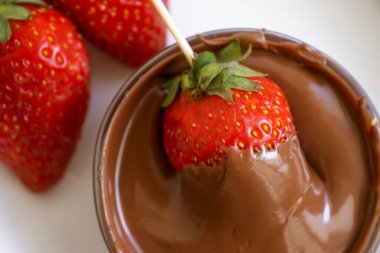 Hafif bir arka planda çikolatalı taze çilekler.