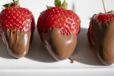 Hafif bir arka planda çikolatalı taze çilekler.