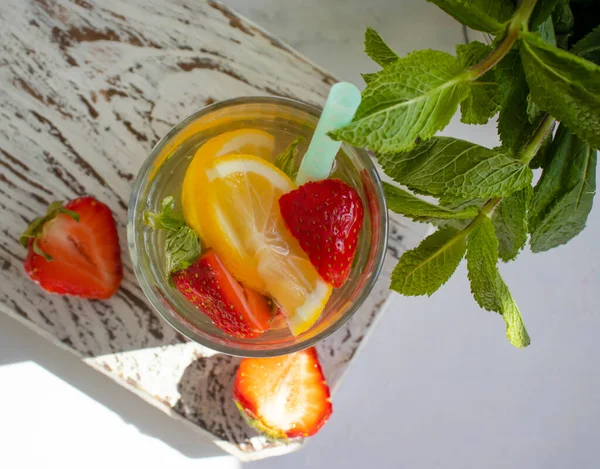 Lemonade with strawberries, mint, lemon on a light background