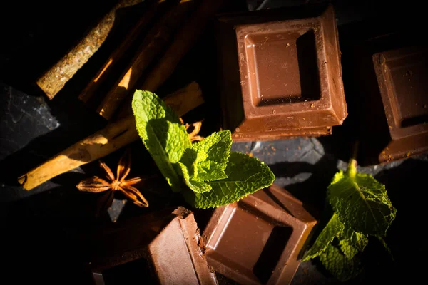 Black chocolate, mint leaf on a dark background