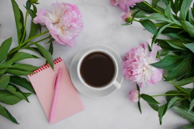 Bir fincan kahve, şakayık çiçeği, arka planda bir defter.