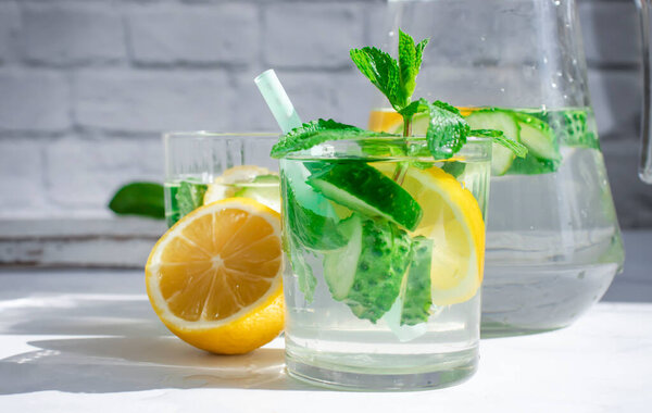 Water with lemon, cucumber, mint on a light background