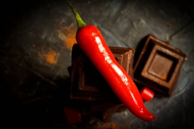 Siyah çikolata, siyah arka planda kırmızı biber.