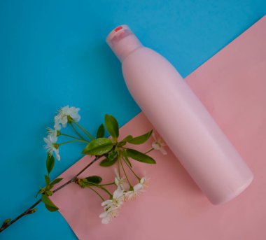 Hafif arka planda kiraz çiçekli kozmetik krem şişesi