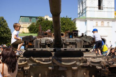 19 Haziran 2022 Ukrayna, Kyiv şehri, çocuklar şehir merkezindeki bozuk Rus tanklarının üzerinde duruyorlar.