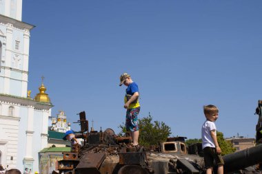 19 Haziran 2022 Ukrayna, Kyiv şehri, çocuklar şehir merkezindeki bozuk Rus tanklarının üzerinde duruyorlar.