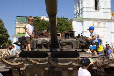 19 Haziran 2022 Ukrayna, Kyiv şehri, çocuklar şehir merkezindeki bozuk Rus tanklarının üzerinde duruyorlar.