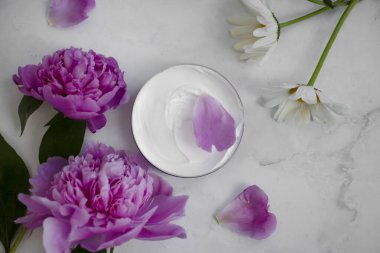 Kozmetik krem, arka planda şakayık çiçeği, papatya çiçeği.