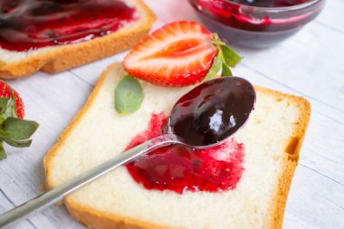 Ekmek, taze çilek, ahşap arka planda reçel.