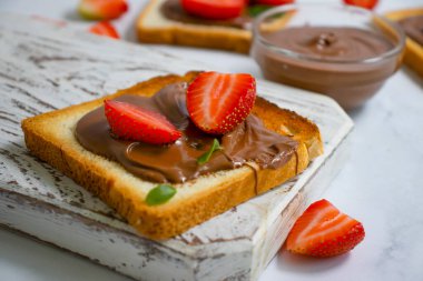 Çikolata ezmeli ekmek, arka planda çilek.