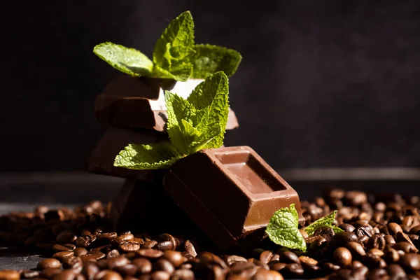 Chocolate, mint leaf, coffee beans on a dark background