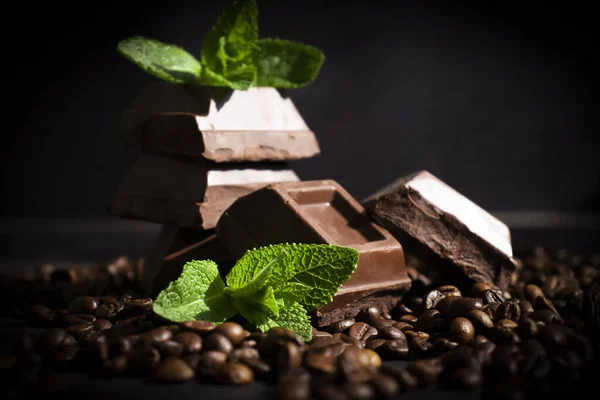 Chocolate, mint leaf, coffee beans on a dark background