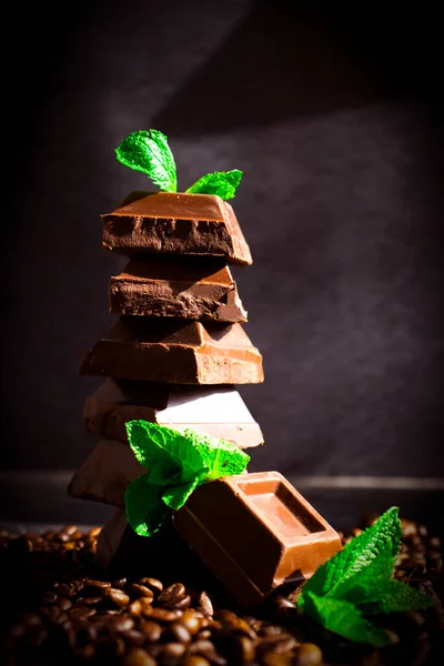 Chocolate, mint leaf, coffee beans on a dark background