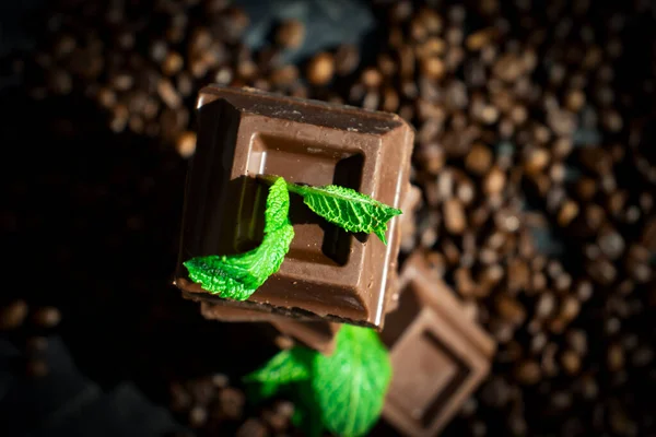 Chocolate, mint leaf, coffee beans on a dark background