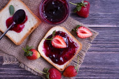 Strawberry jam, bread, fresh berry on a wooden background