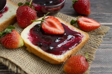 Strawberry jam, bread, fresh berry on a wooden background