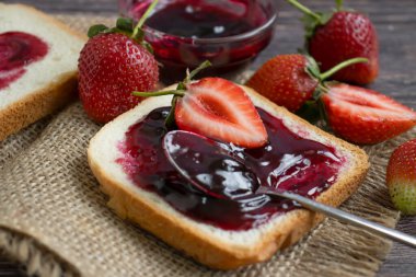 Strawberry jam, bread, fresh berry on a wooden background