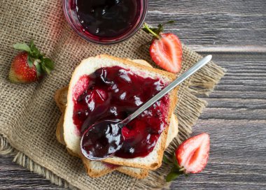 Strawberry jam, bread, fresh berry on a wooden background